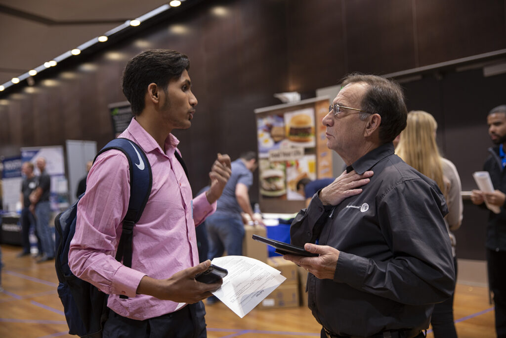 A student and a potential employer talk during the career fair.