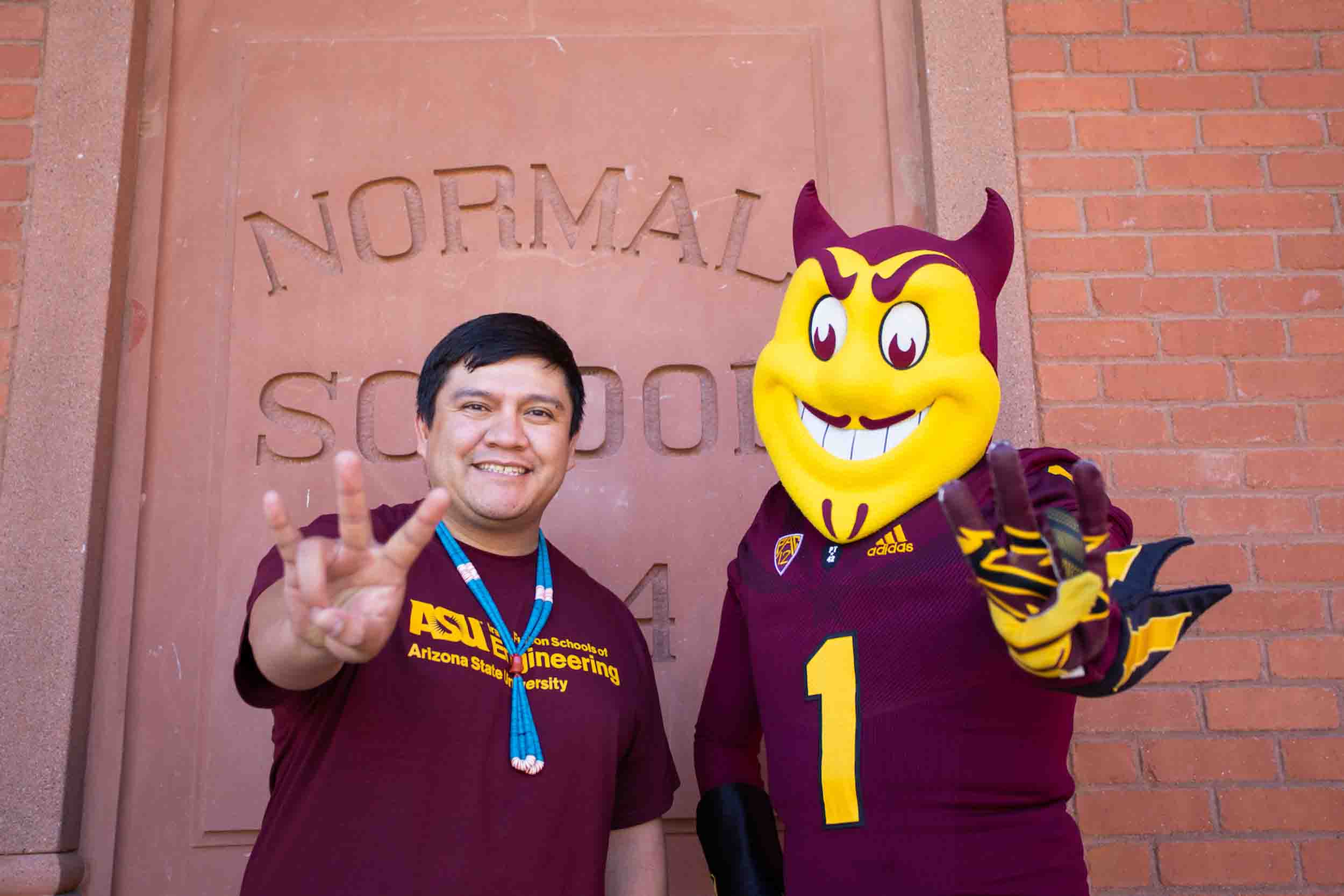 Royce Perez poses with mascot Sparky in front of ASU's Old Main building.