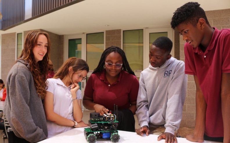 A group of five students surrounds a small drone.