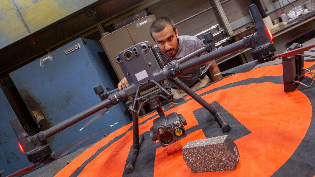 ASU Engineering student Othman Al-Alawi looks closely at a large drone in a lab
