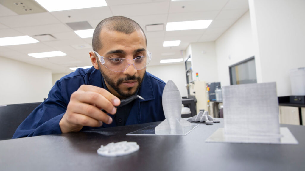 Mohammed Bawareth observes a shape created through additive manufacturing (3D printing)