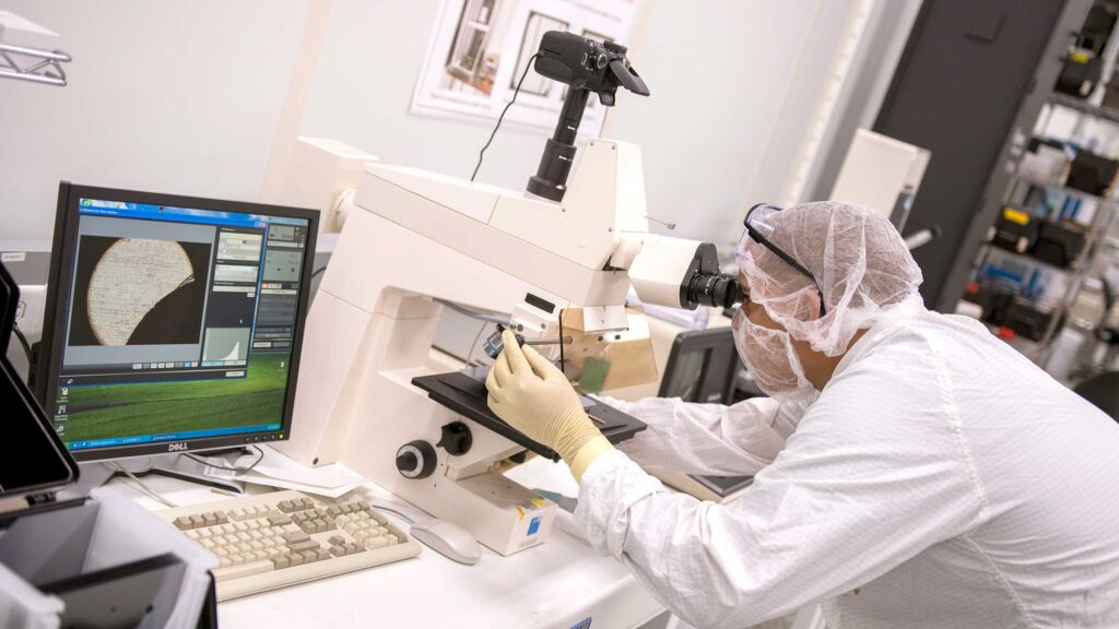Researcher looking through microscope in a lab.