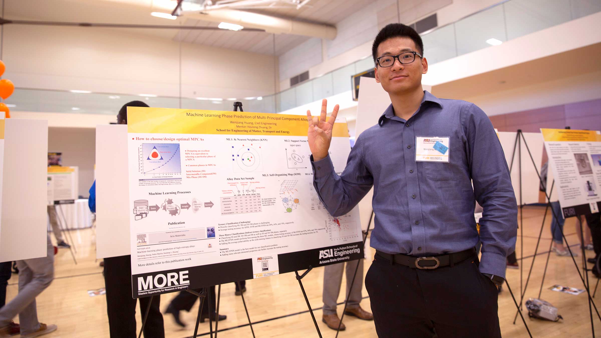 A student poses in front of his project poster.