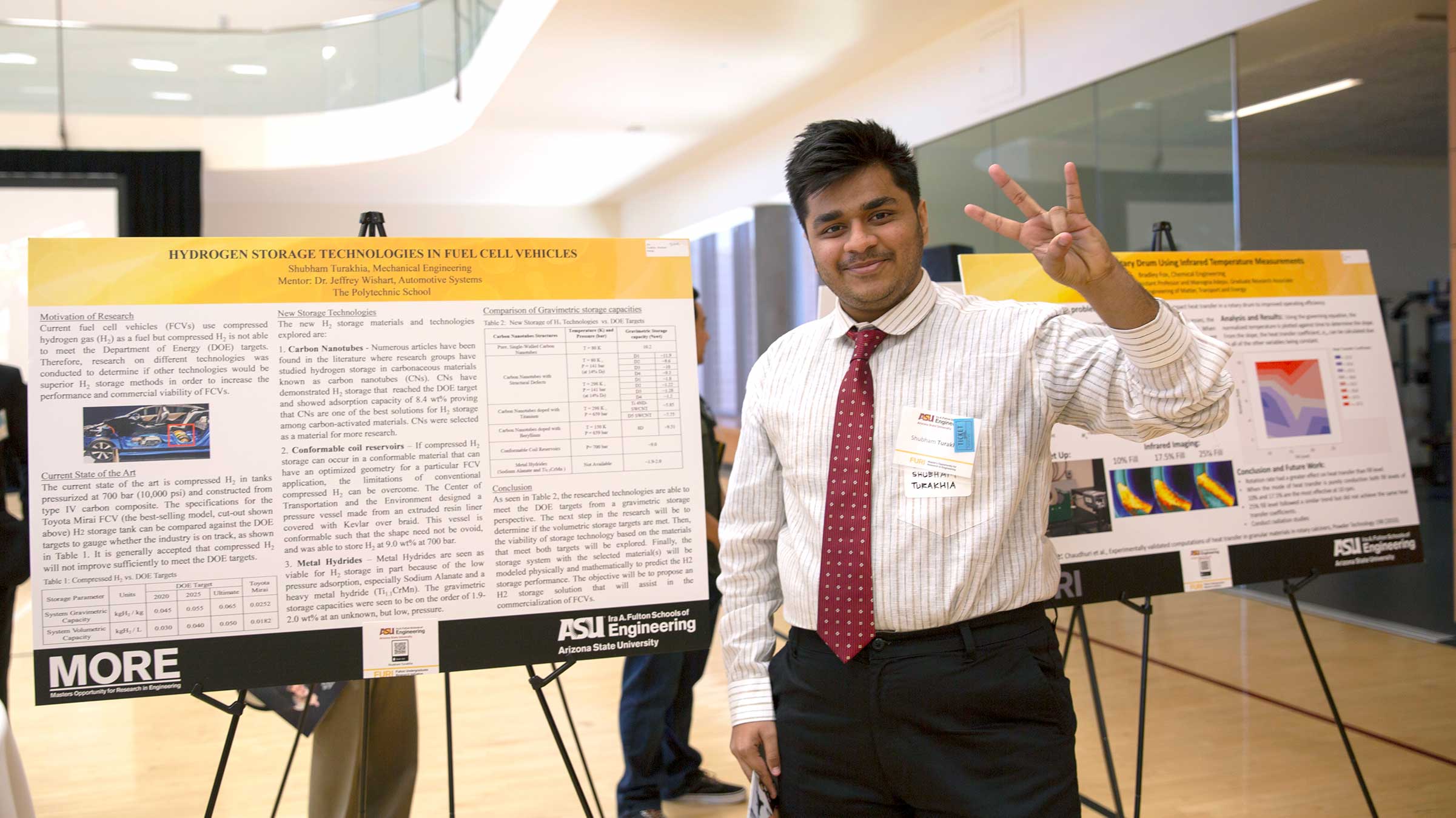 A student poses in front of his project poster.