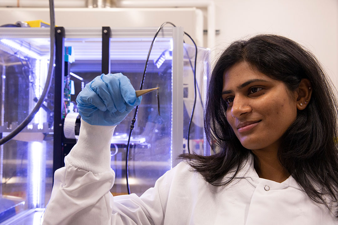Engineering student Mounika Kakarla closely observing a small object at an ASU research facility.