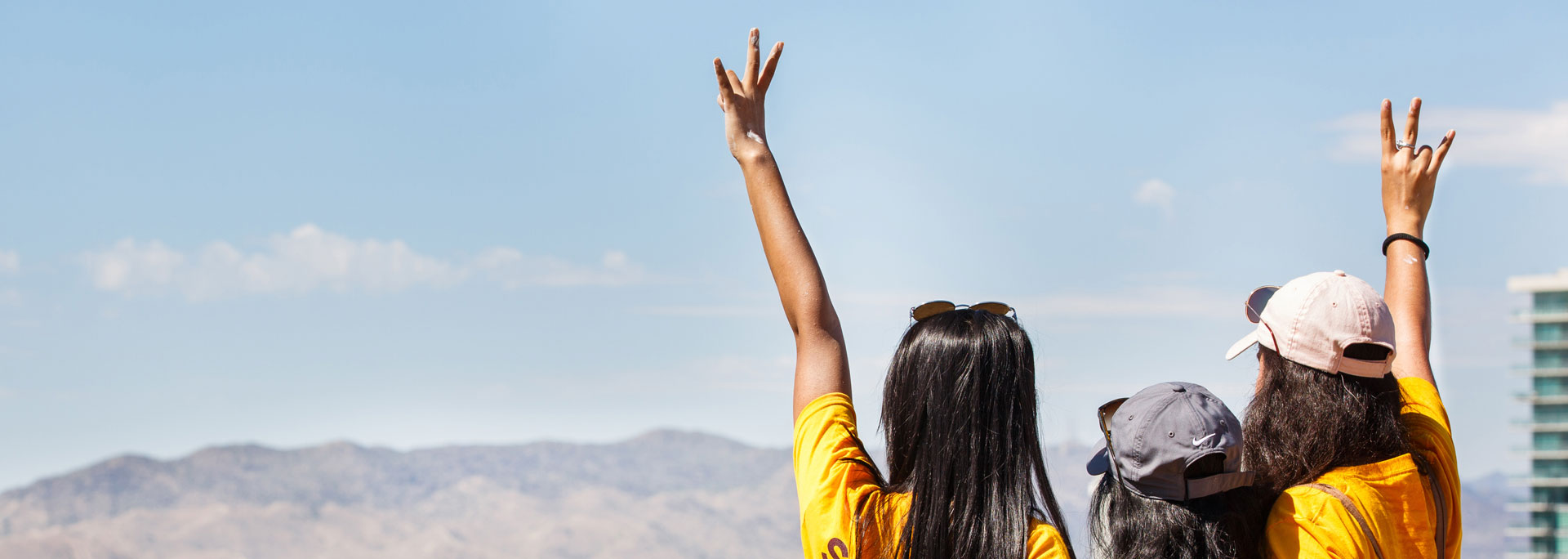 Three women stand atop A Mountain and throw up the fork hand signal.