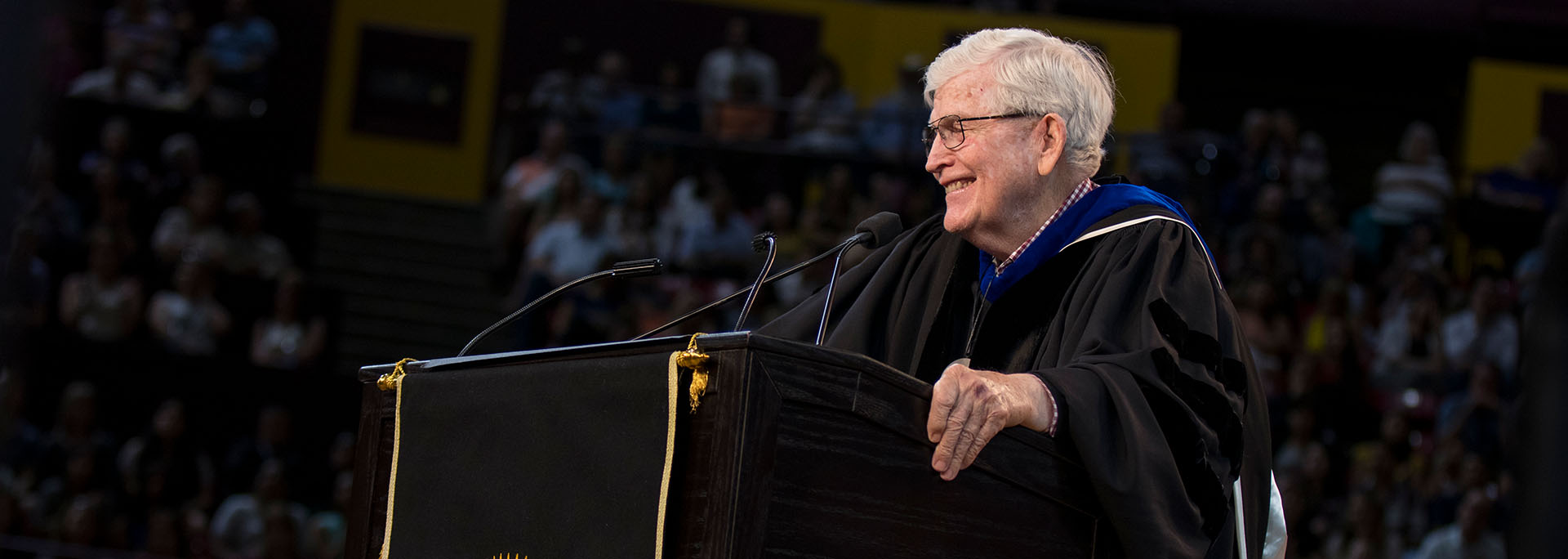 Ira A. Fulton stands at the podium during the ASU Engineering Convocation ceremony, smiling while he addresses the crowd.